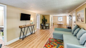 A living room with a sofa, a TV mounted on the wall, a wooden coffee table, and a colorful rug. - Middle Tennessee Cottage ~ 10 Mi to Dickson! (Bon Aqua)