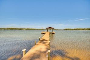 A wooden pier extending into calm water, leading to a gazebo.