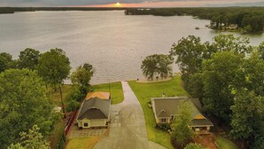A residential area with two houses, a driveway, and a body of water in the background. - Lakefront Gem: Hot Tub, Boat Launch Near Greenwood (Cross Hill)