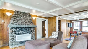 Una sala de estar acogedora con chimenea de piedra, paredes de madera y un área de descanso confortable.