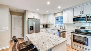 A modern kitchen with white cabinets, stainless steel appliances, and a granite countertop. - Charming Pinehurst Getaway w/ Golf Course View! (Pinehurst)