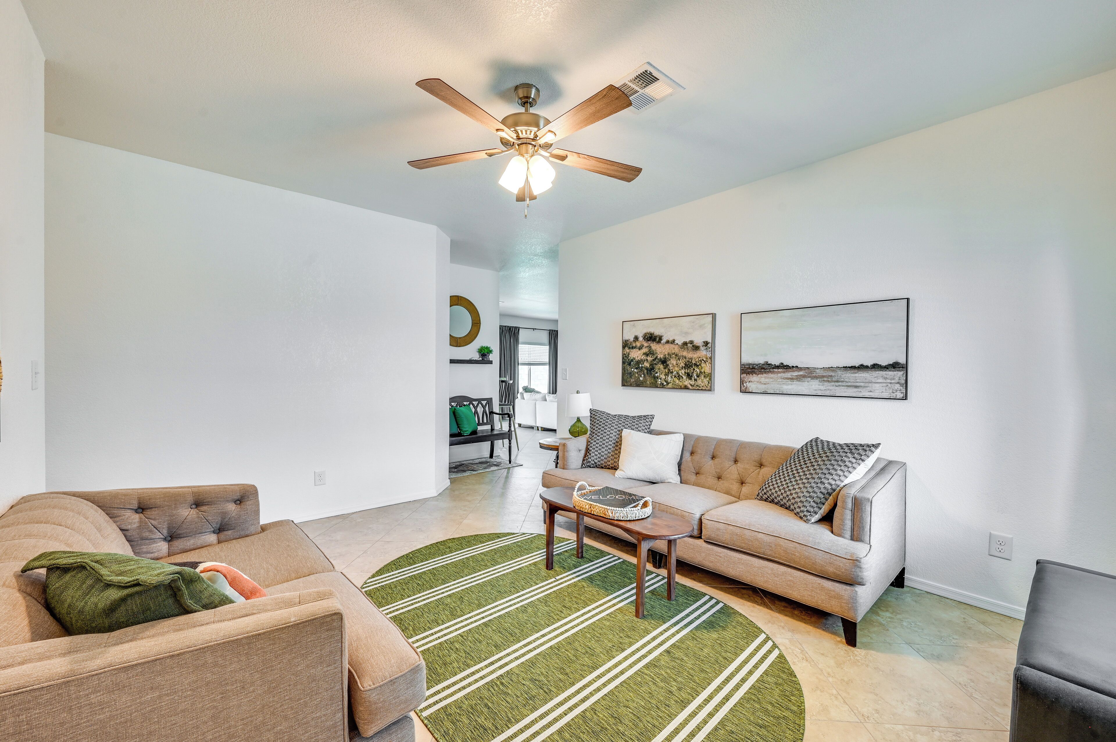 A spacious living room with a ceiling fan, a sofa, a coffee table, and a rug.