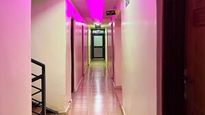 A hallway with pink lighting, a tiled floor, and a staircase on the left. - Sky Park Lounge (Nairobi)