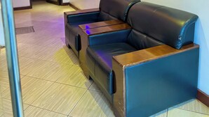 A modern living room with a sectional sofa, built-in shelves with decorative items, and a unique ceiling design with integrated lighting. - Sky Park Lounge (Nairobi)