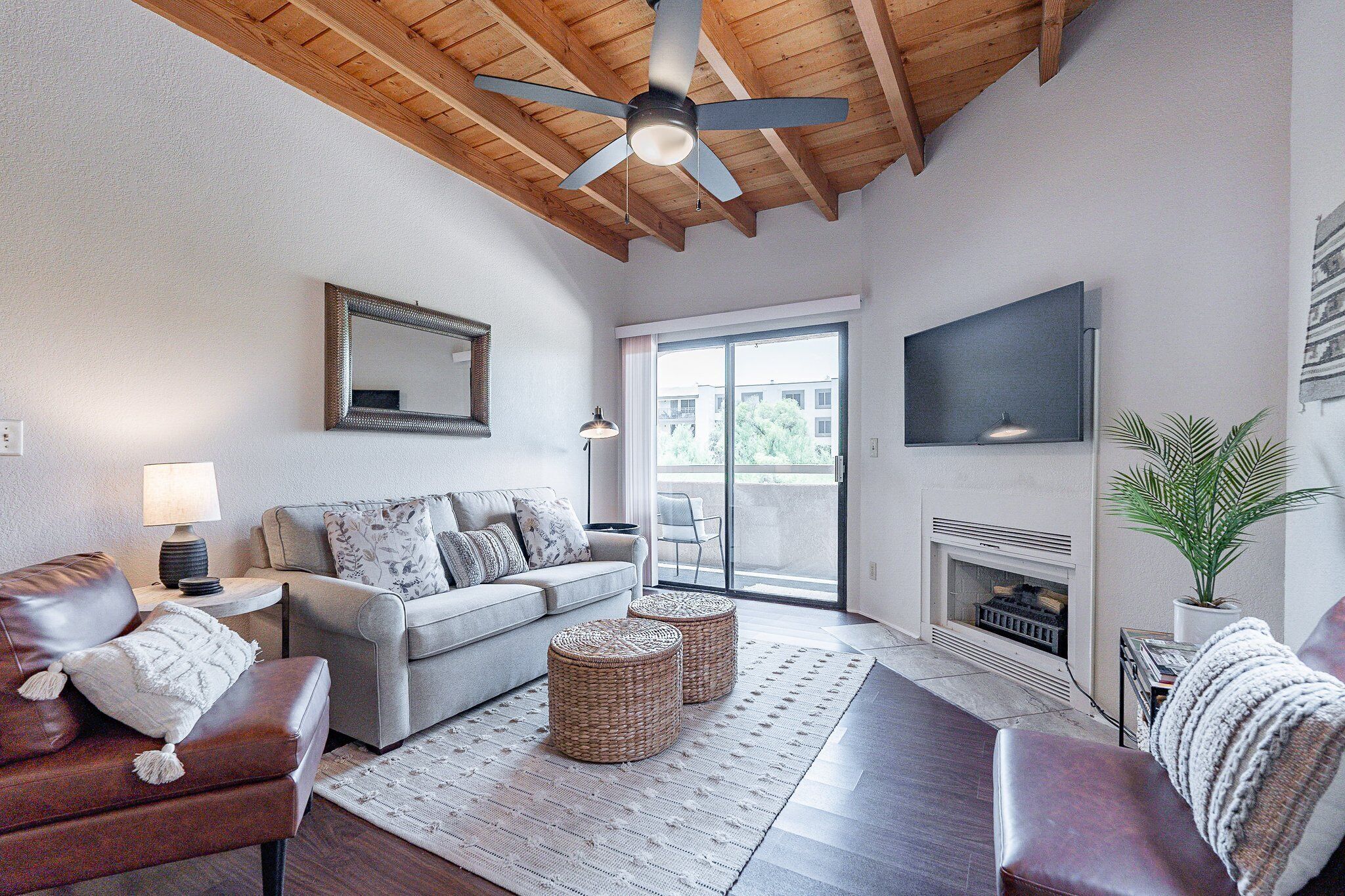 A living room with a ceiling fan, a fireplace, a sofa, a coffee table, and a television.