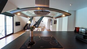 Eine moderne Küche mit einer zentralen Kochinsel, einem integrierten Herd und einem großen Fenster, das für natürliches Licht sorgt.