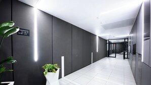 A modern hallway with directional signs, white flooring, and potted plants. - Native Apartments Barska 69 (Kraków)