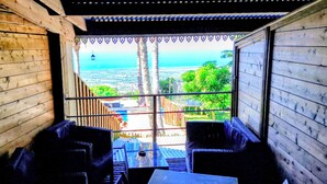 Un intérieur en bois offrant une vue sur la mer et un balcon aménagé avec des sièges.
