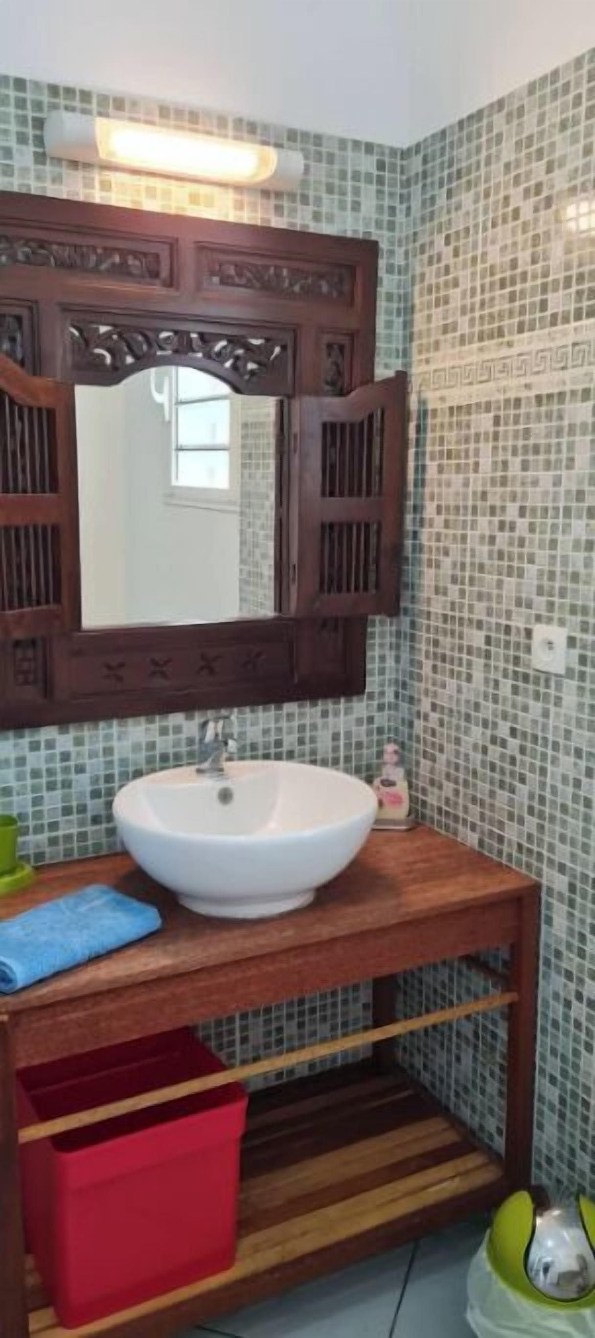 A bathroom with a wooden vanity, a white sink, and a mirror with a decorative frame.