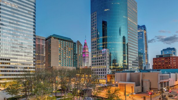 A cityscape with modern high-rise buildings, including a prominent glass skyscraper and a building with a 'Xactly' sign. - Prime location Downtown Denver Cozy 2-bedroom condo in peaceful Denver (Denver)