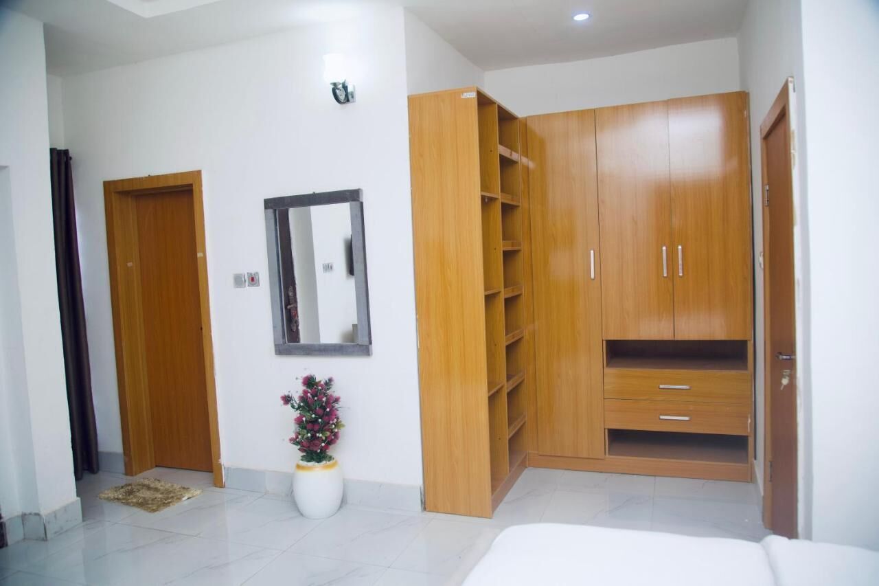 A room with a large wooden wardrobe, a small potted plant, and a mirror on the wall.