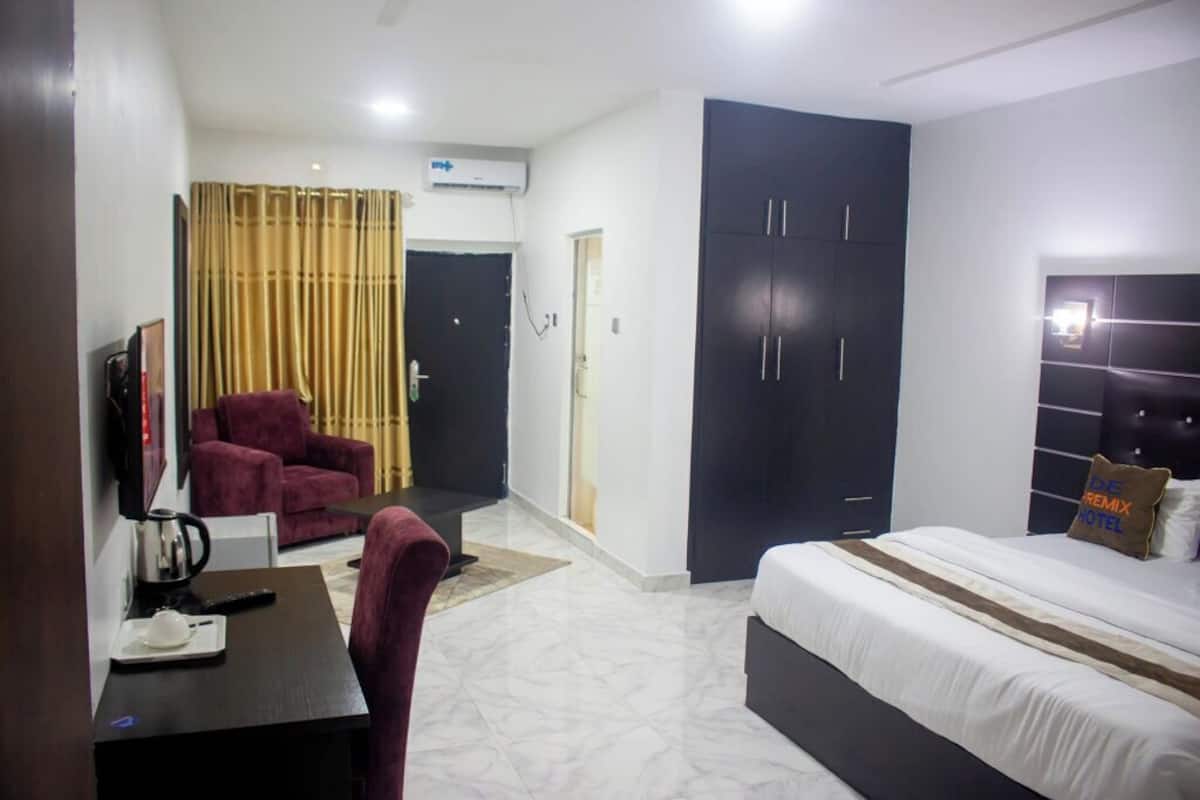 A hotel room with a bed, a desk with a chair, a TV, a wardrobe, and a curtain.