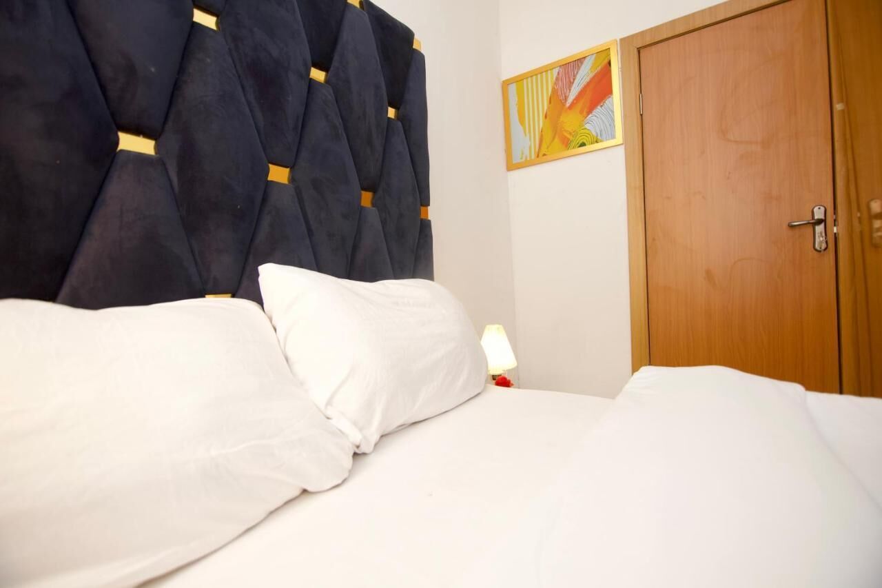 A bed with white bedding and a dark headboard with yellow accents.