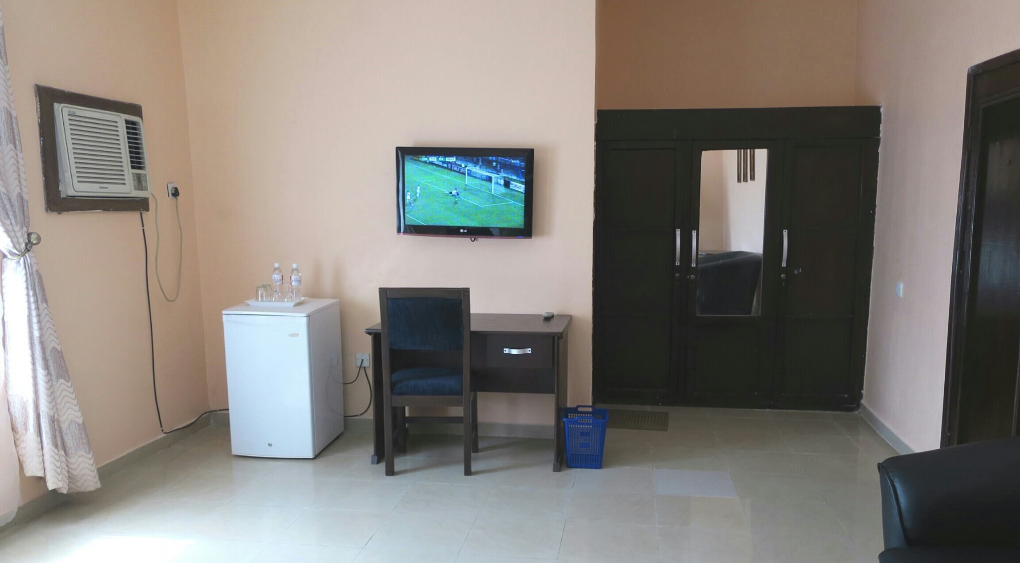 Una habitación con escritorio, silla, televisor y una puerta.
