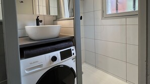 A compact bathroom with a white sink, a mirror, and a built-in washing machine. - T2 Apartment in Quiet Area Near Slopes, Corrençon-en-Vercors (Corrençon-en-Vercors)