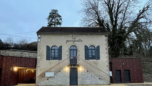 Un bâtiment avec un escalier menant à une porte, sur laquelle est inscrit le mot « La gunguette ».