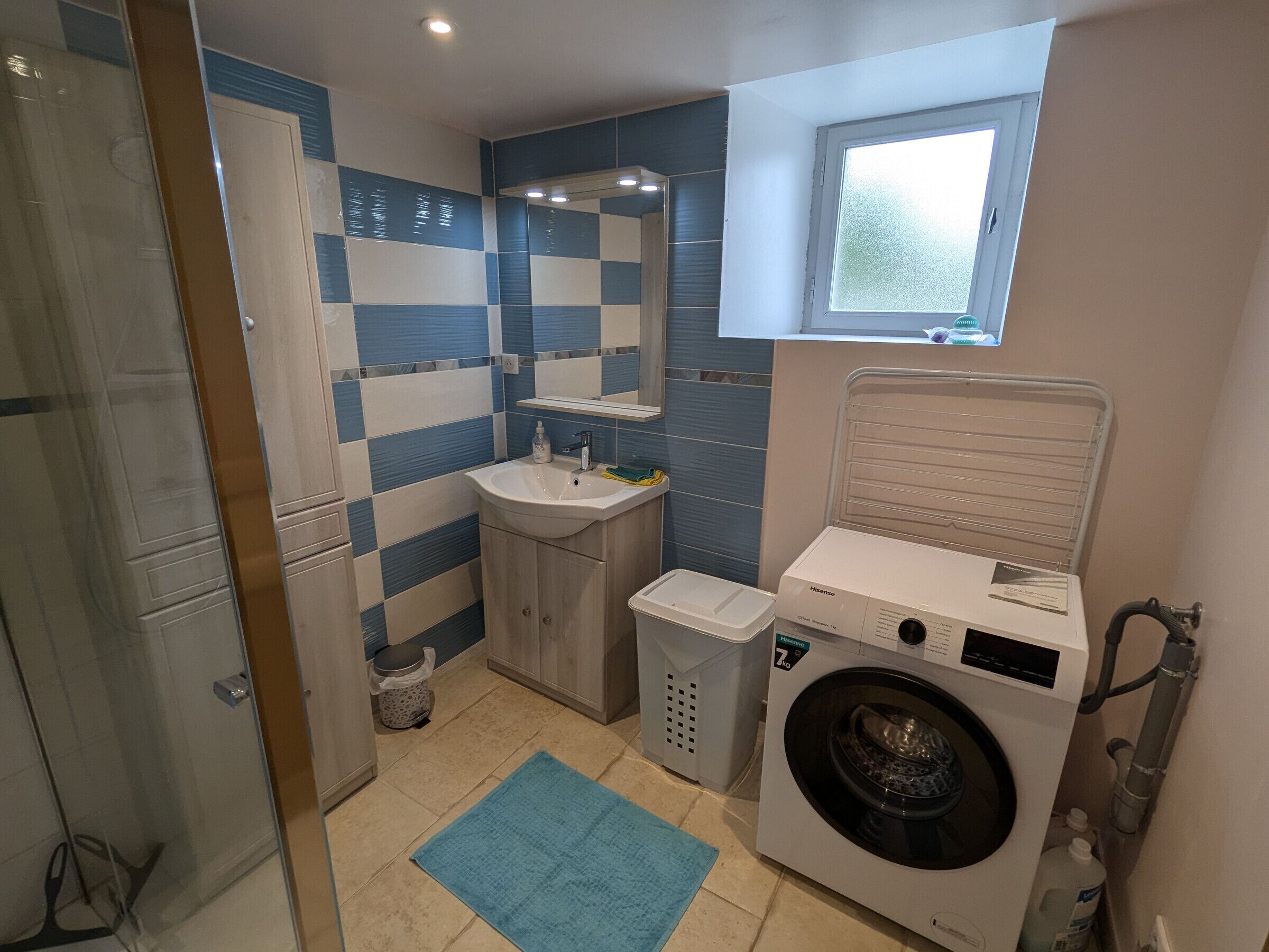 Une petite salle de bain comprenant un lavabo, un miroir et un lave-linge.