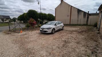 A white car parked in a gravel driveway with a building in the background.
