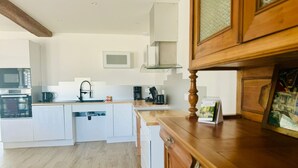 A modern kitchen with white cabinetry, a wooden countertop, and a built-in oven. - Charming cottage in Vendée with spa and sauna (La Roche-sur-Yon)