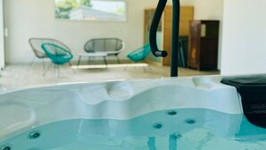 A hot tub with a wooden ceiling and a view of a room with two chairs and a table. - Charming cottage in Vendée with spa and sauna (La Roche-sur-Yon)