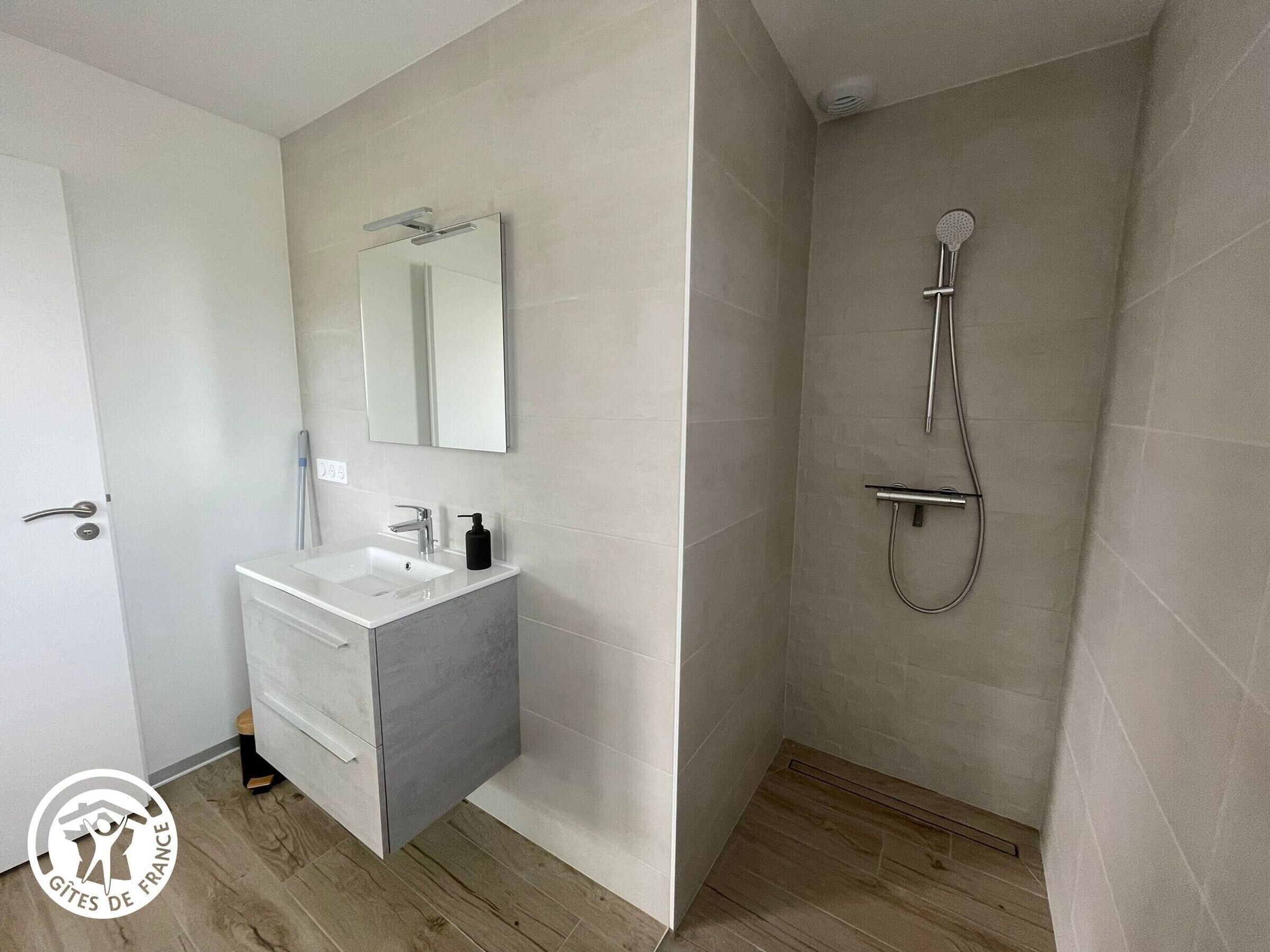 Ein modernes Badezimmer mit Waschbecken, Spiegel und Dusche.