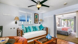 Una habitación con cama, sofá, mesa de centro y ventilador de techo.