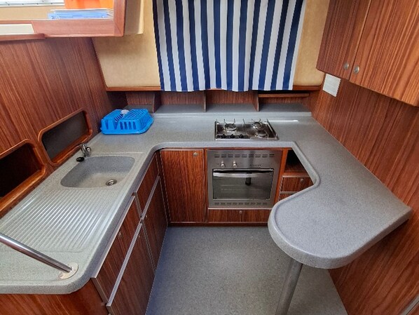 A compact kitchenette with a sink, stove, oven, and a small countertop.