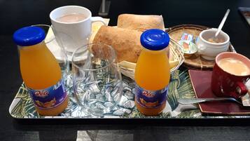 A tray with breakfast items including orange juice, a cup of coffee, a sandwich, and a bowl of yogurt.