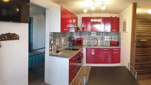 Una cocina compacta con gabinetes rojos, un microondas y un salpicadero decorado.