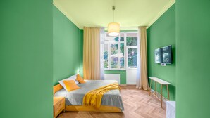 A bedroom with a bed, bedside table, and a TV mounted on the wall. - HB apartments Astoria (Tbilisi)
