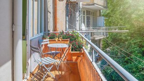 A balcony with a table and chairs, a potted plant, and a view of the surrounding greenery. - HB apartments Astoria (Tbilisi)