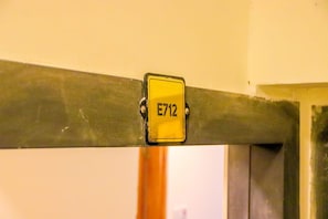 A yellow sign with the number 'E712' attached to a metal structure. - Studio Sleeps 2 With 24hr Check-in (Syokimau)