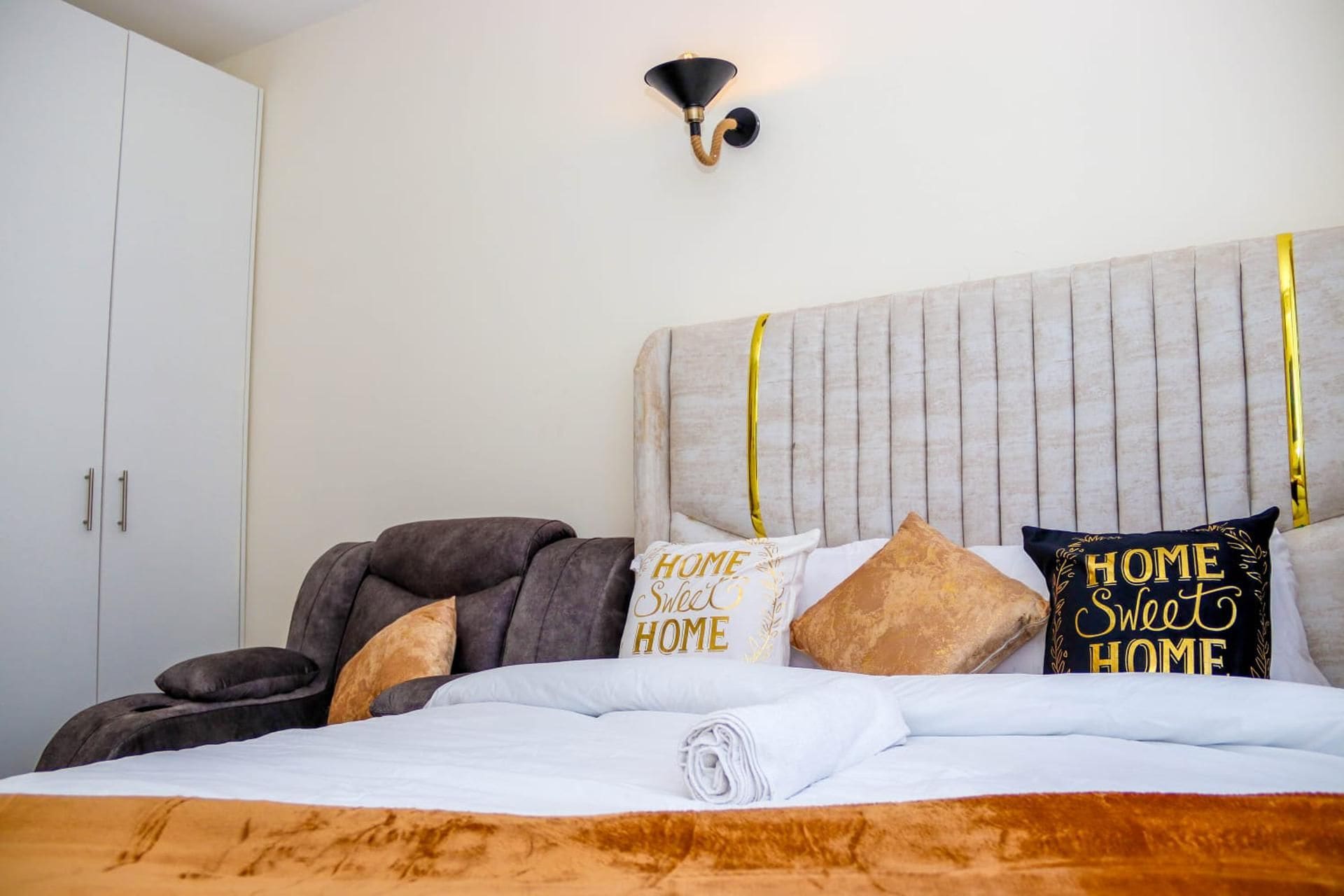 Ein Schlafzimmer mit einem Bett, Kissen, einem Kopfteil und einer Wandleuchte.