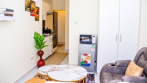 A compact living space with a kitchen, a dining area with a marble table, and a gray sofa. - Studio Sleeps 2 With 24hr Check-in (Syokimau)