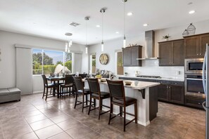 A modern kitchen with a central island, bar stools, and built-in appliances.