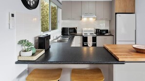 A modern kitchen with a central island, built-in appliances, and a large window.
