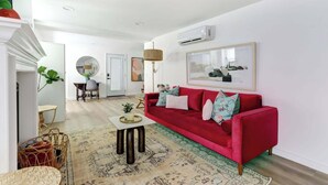 A modern living room with a red sofa, a round coffee table, and a large mirror.