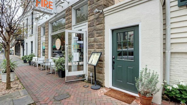 A brick-paved sidewalk, a storefront with a 'FREE' sign, a green door, and outdoor seating.