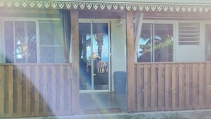 Una casa con un portico in legno, una porta scorrevole in vetro e una finestra con persiane.