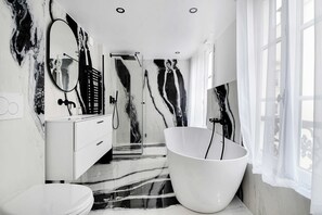 A modern bathroom with a large bathtub, a walk-in shower, and a vanity with a mirror. - Résidence Paris Havre (Paris)