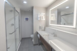 Un baño moderno con cabina de ducha de vidrio, un lavabo blanco y un espejo grande.