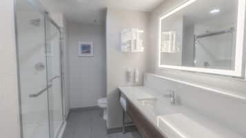 A modern bathroom with a glass shower enclosure, a white sink, and a large mirror.
