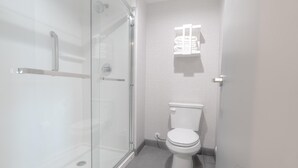 Un baño moderno con cabina de ducha de vidrio, inodoro y toallero.
