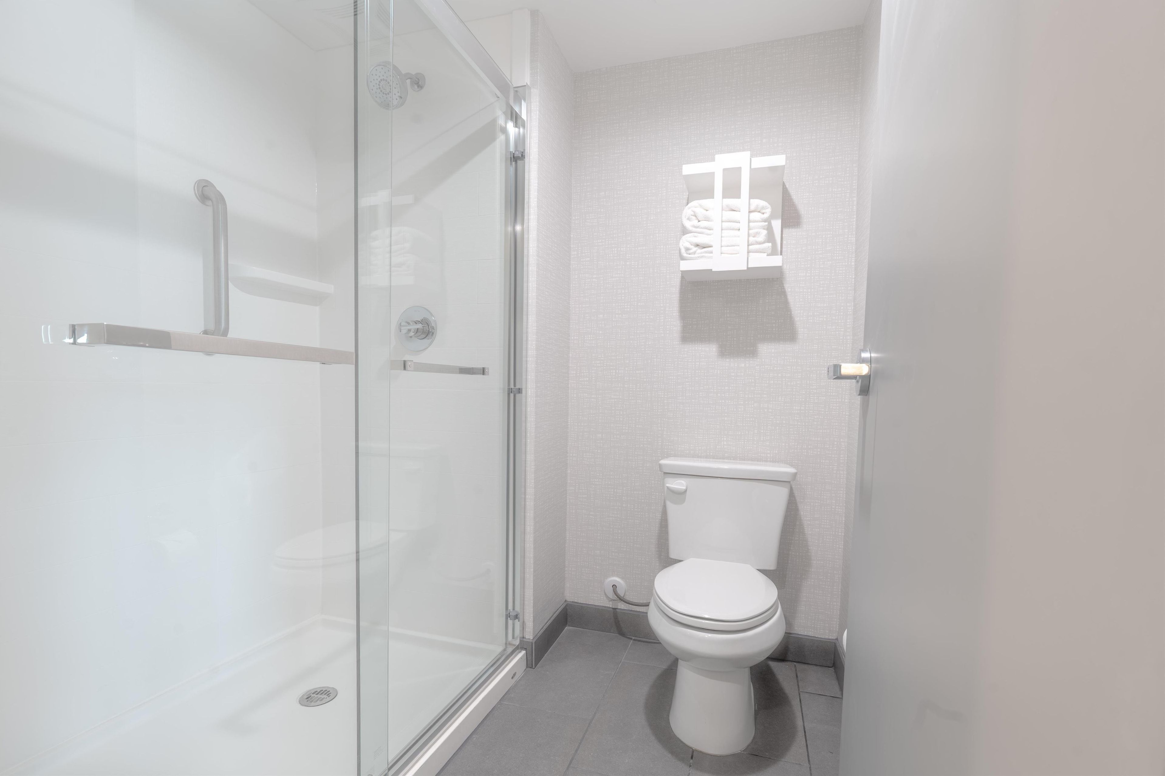 Un baño moderno con cabina de ducha de vidrio, inodoro y toallero.