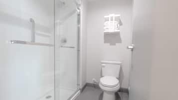 Un baño moderno con cabina de ducha de vidrio, inodoro y toallero.