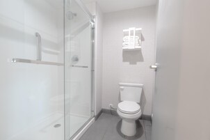 Un baño moderno con cabina de ducha de vidrio, inodoro y toallero.