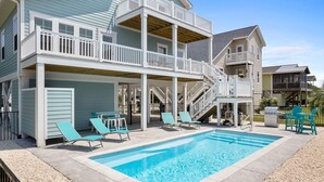 A two-story building with a pool, outdoor seating, and a barbecue grill.