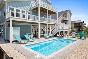 A two-story building with a pool, outdoor seating, and a barbecue grill.