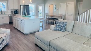 A spacious living area with a large island, a sofa, and a dining table.
