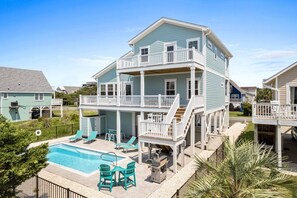 A two-story house with a balcony, a swimming pool, and outdoor furniture.